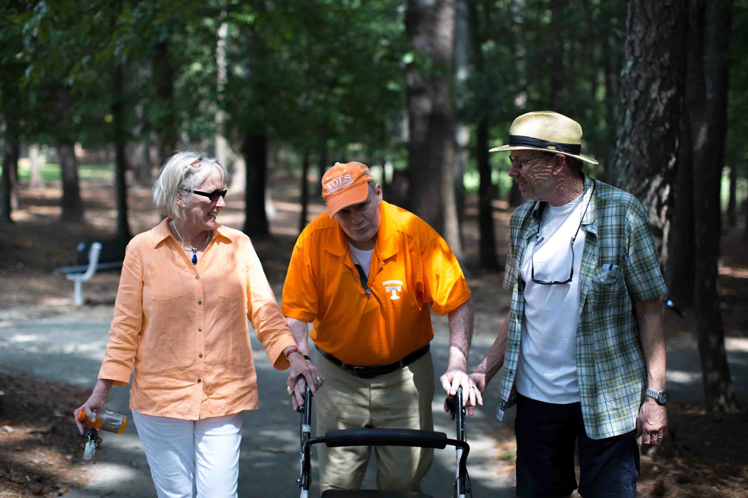 Walter Chadwick, center, who was a star running back at the University of Tennessee, walks with his friend and University of Tennessee alum Ellen Morrison, left, and former Wills High School football player Keith Miller in Laurel Park, Sunday, Aug. 28, 2016, in Marietta, Ga. Chadwick was named head coach of Wills High School in 1971, but after only being on the job just two weeks, a Wells Fargo armored van slammed into him leaving Chadwick permanently brain damaged. Chadwick recently gathered with friends and former students, many of whom thought he was dead. (Branden Camp for The Atlanta-Journal Constitution)