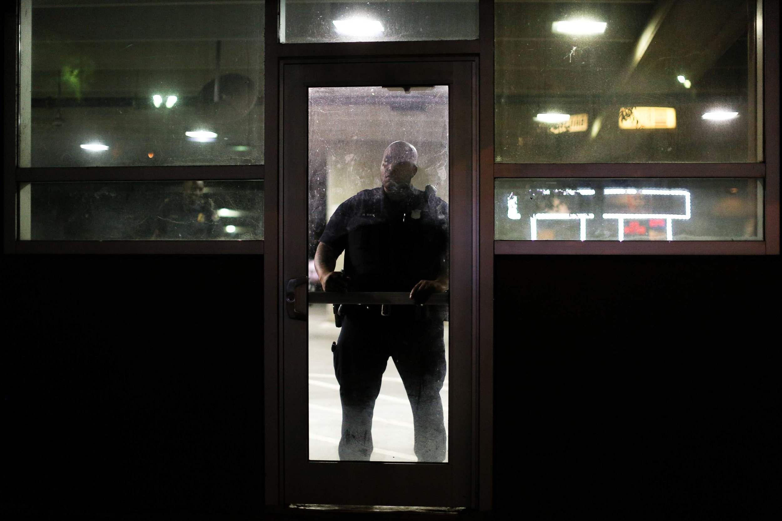 An Atlanta police officer watches demonstrators march during a protest in Atlanta on Friday, Sept. 23, 2016 in response to the police shooting deaths of Terence Crutcher in Tulsa, Okla. and Keith Lamont Scott in Charlotte, N.C. (AP Photo/Branden Camp)