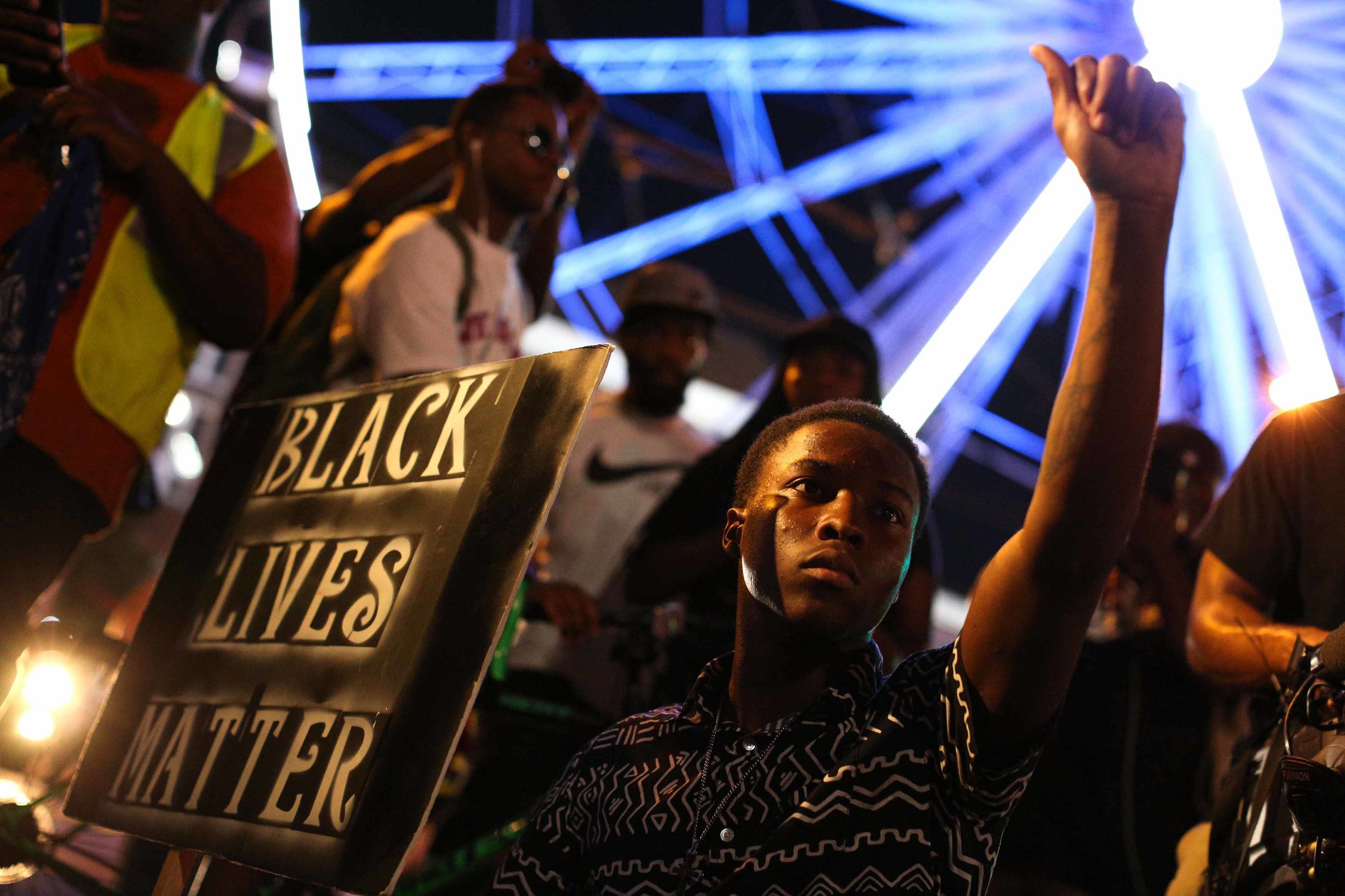 A demonstrator holds a sign during a protest in Atlanta on Friday, Sept. 23, 2016 in response to the police shooting deaths of Terence Crutcher in Tulsa, Okla. and Keith Lamont Scott in Charlotte, N.C. (AP Photo/Branden Camp)