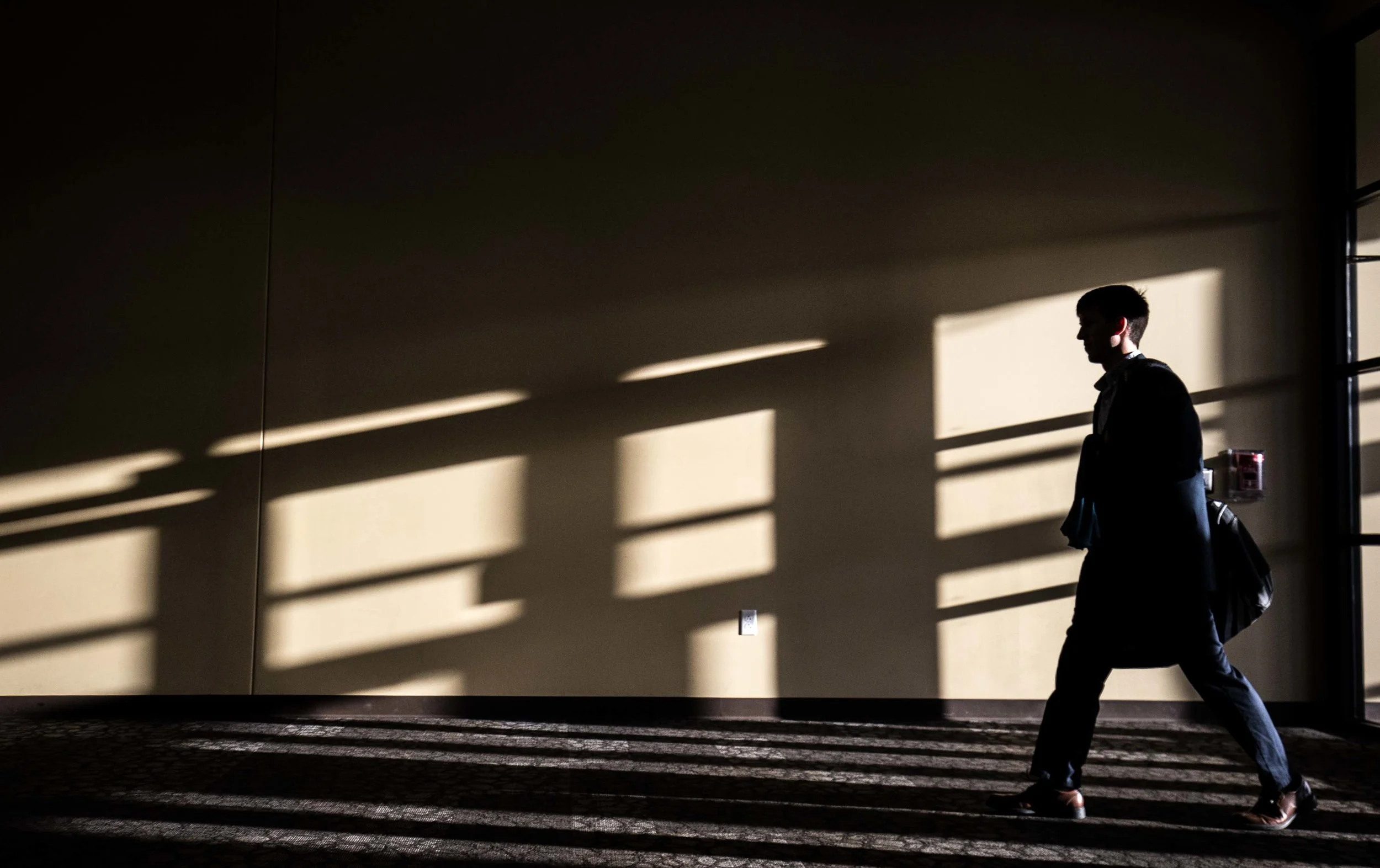A man walks through a church as sunlight shines on a wall in Indianapolis. Photo by Branden Camp