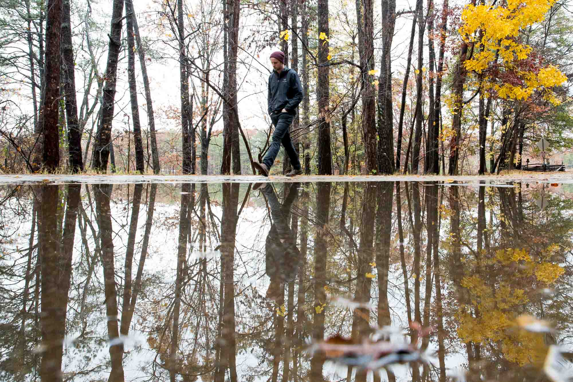 A man is reflected in a puddle of water at the base of Kennesaw Mountain on an overcast day. Branden Camp for AJC