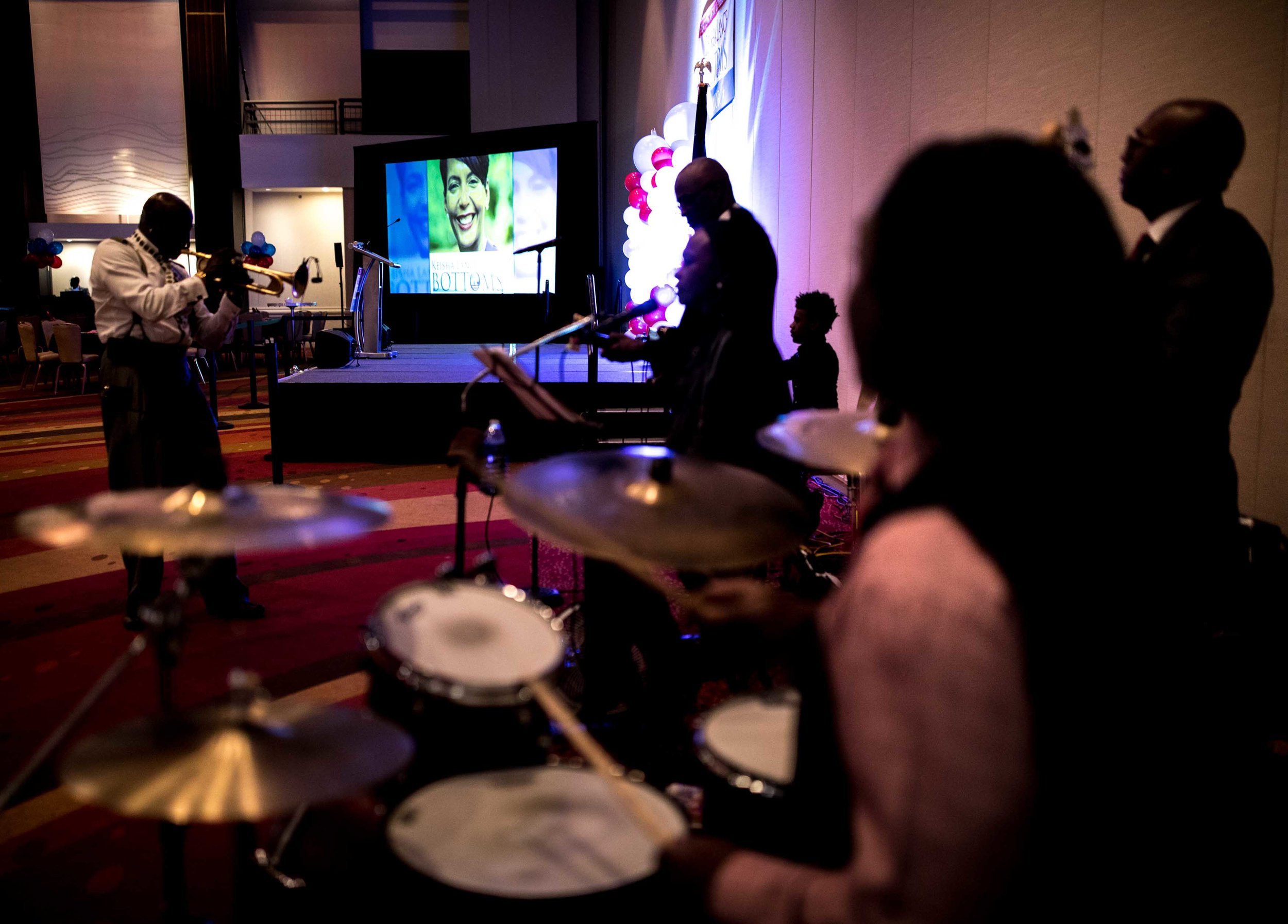 A photo of Keisha Lance Bottoms is displayed on a screen as a band warms up before an election party.