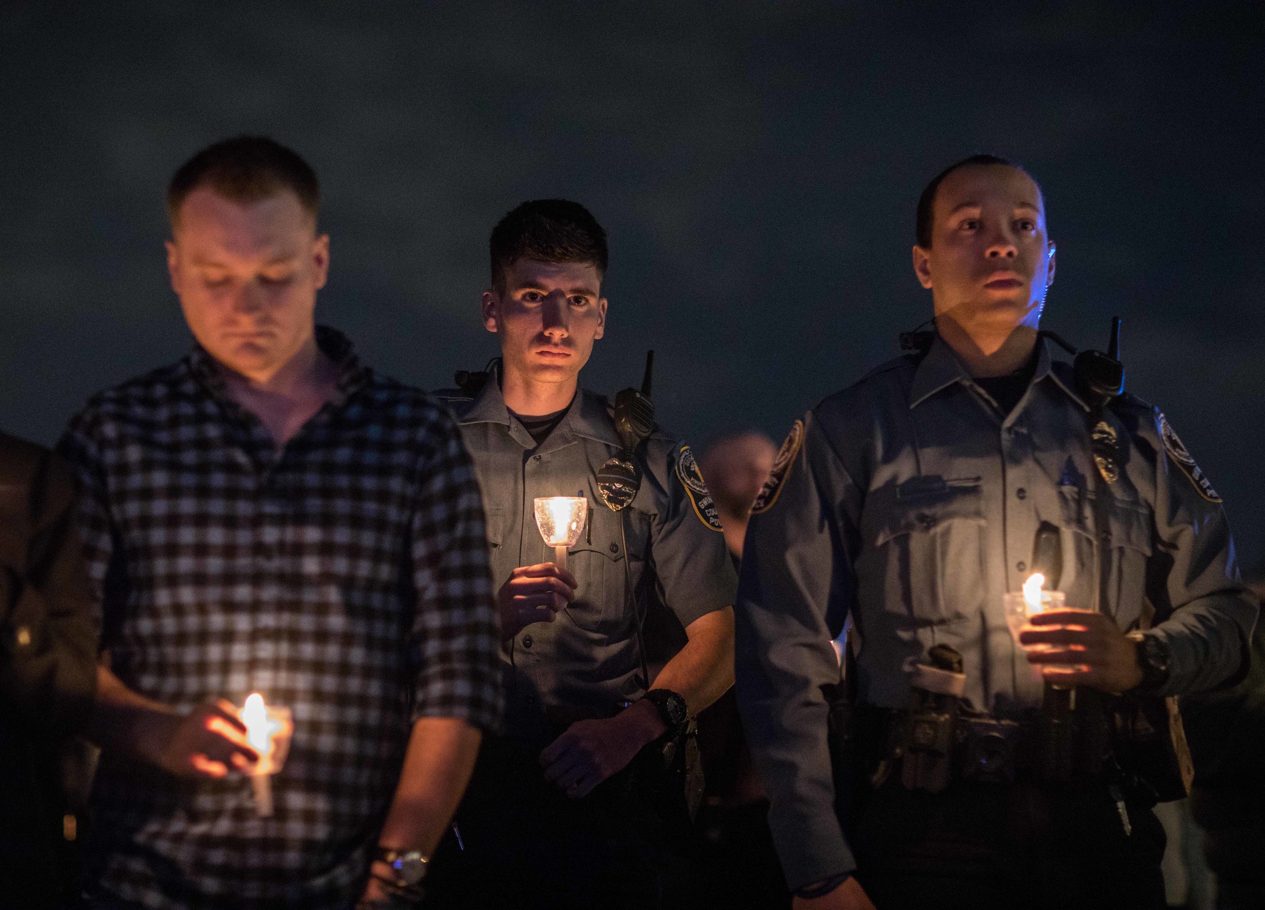 Police officers and members of the community hold candles during a vigil for Gwinnett police officer Antwan Toney, who was killed in the line of duty, at Gwinnett Church, Monday, Oct. 22, 2018, in Sugar Hill, Ga. A Gwinnett County police officer on Monday shot and killed Maynard, 18, accused of fatally shooting police officer Antwan Toney on Saturday near a school in the Atlanta area, police said. (Branden Camp/Atlanta Journal-Constitution via AP)