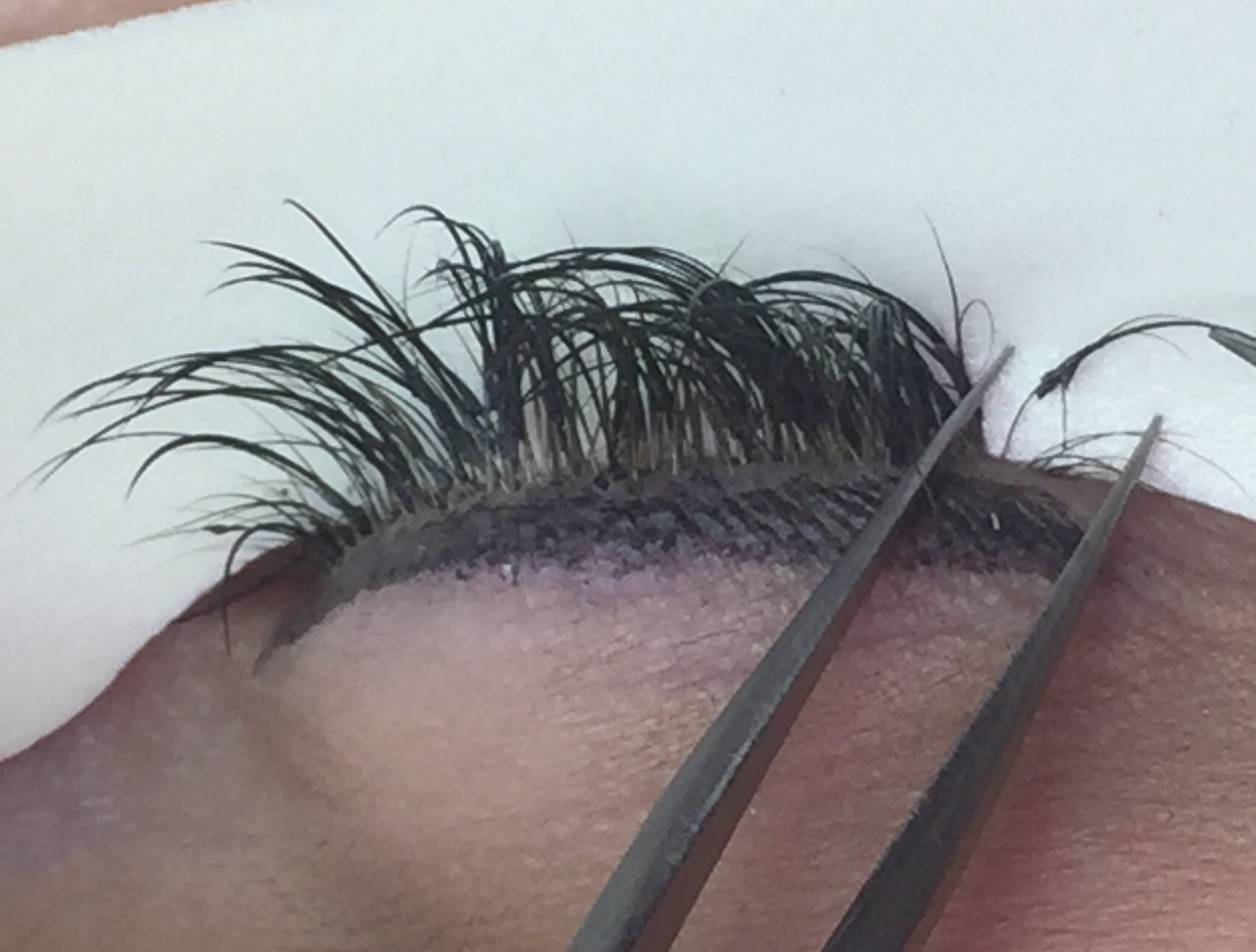 You can see how this extension is attached to multiple hairs and has excess adhesive. The extensions are also placed entirely too far from the base of the lash.&nbsp;