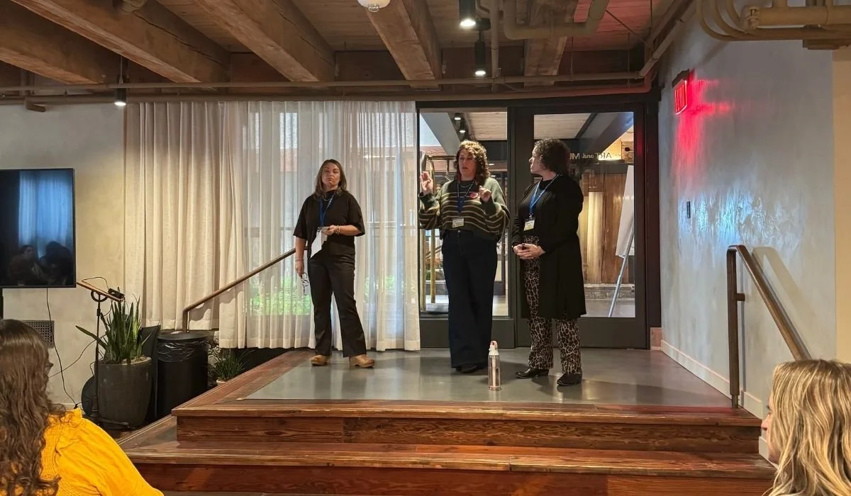 Three women speak on small stage