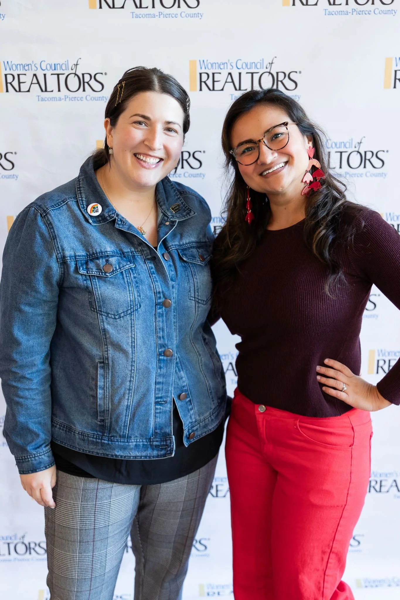 Two women posing in front of a Women's Council of REALTORS Tacoma-Pierce County backdrop