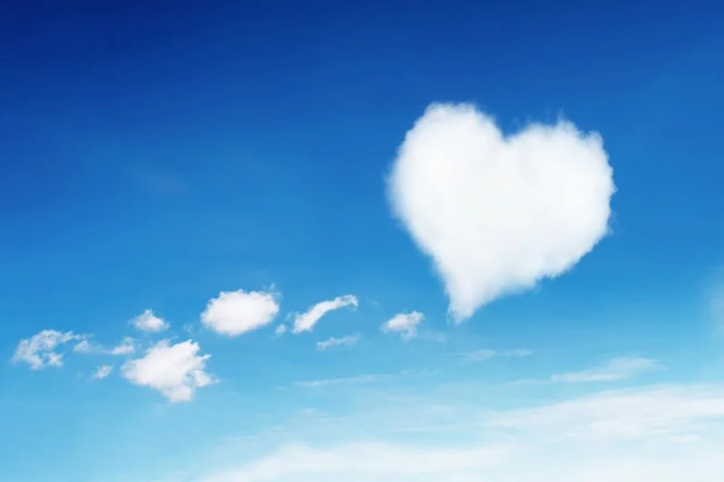 Blue sky with white clouds, including a large heart-shaped cloud.