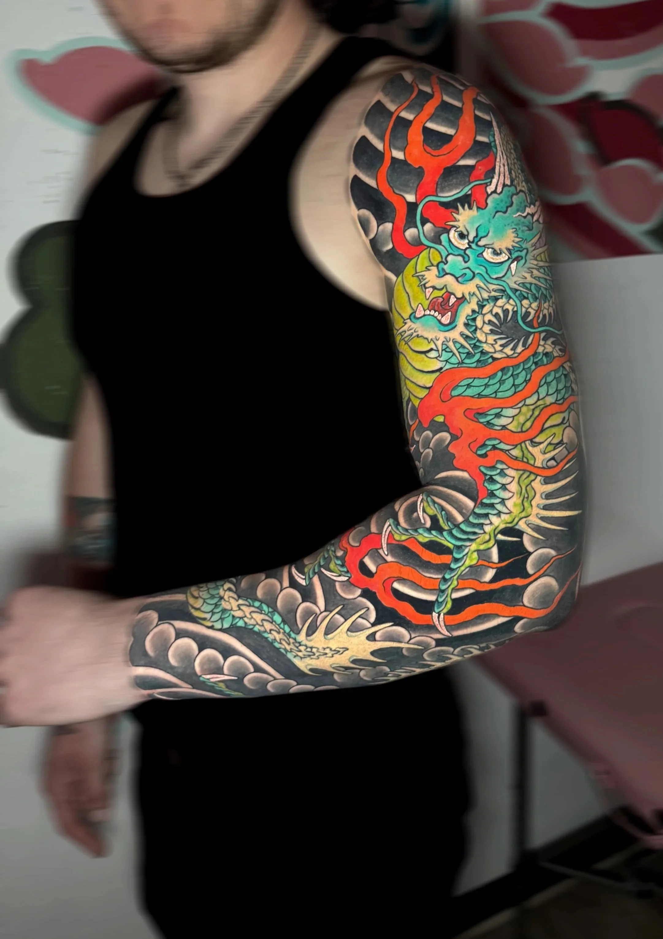 A person with a tattooed arm featuring a colorful dragon design.