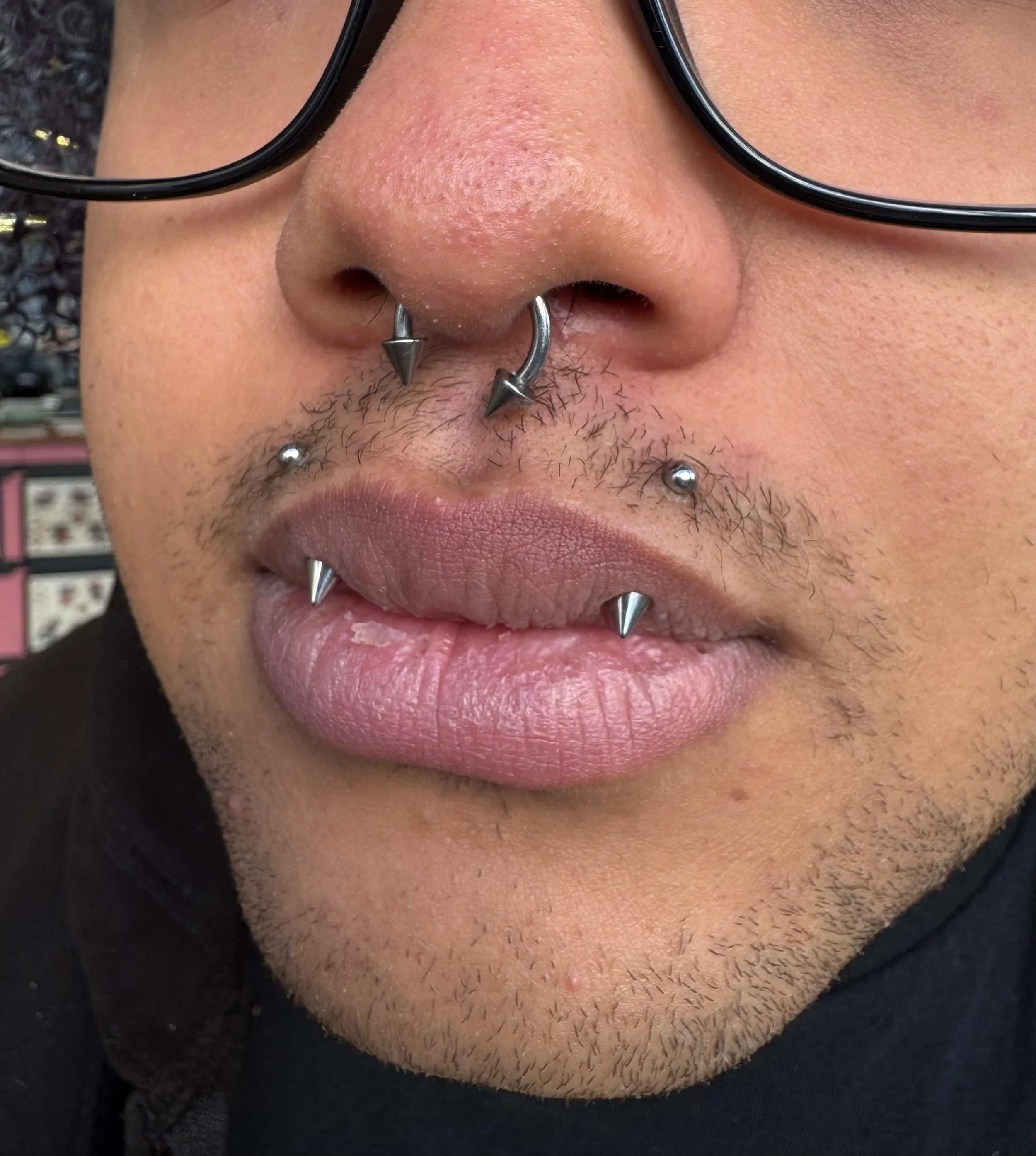 An image of a septum piercing and angel fang lip piercings with spike titanium attachments done at Kilburn Original