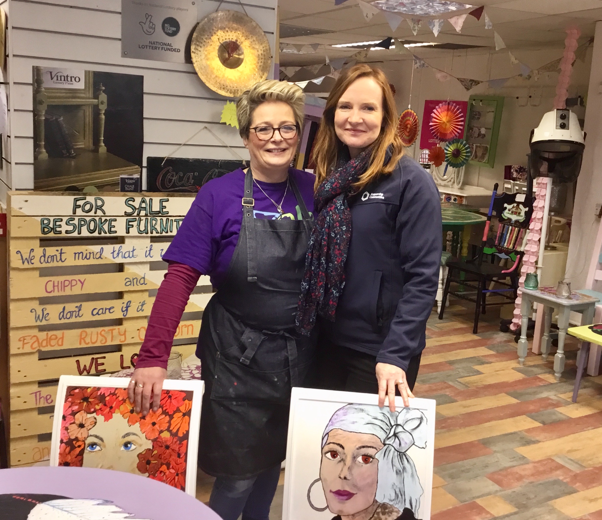 Ailish Teague, LCCL, and Orla McCann, Supporting Communities, pose with some hand painted furniture for sale in the LCCL shop.