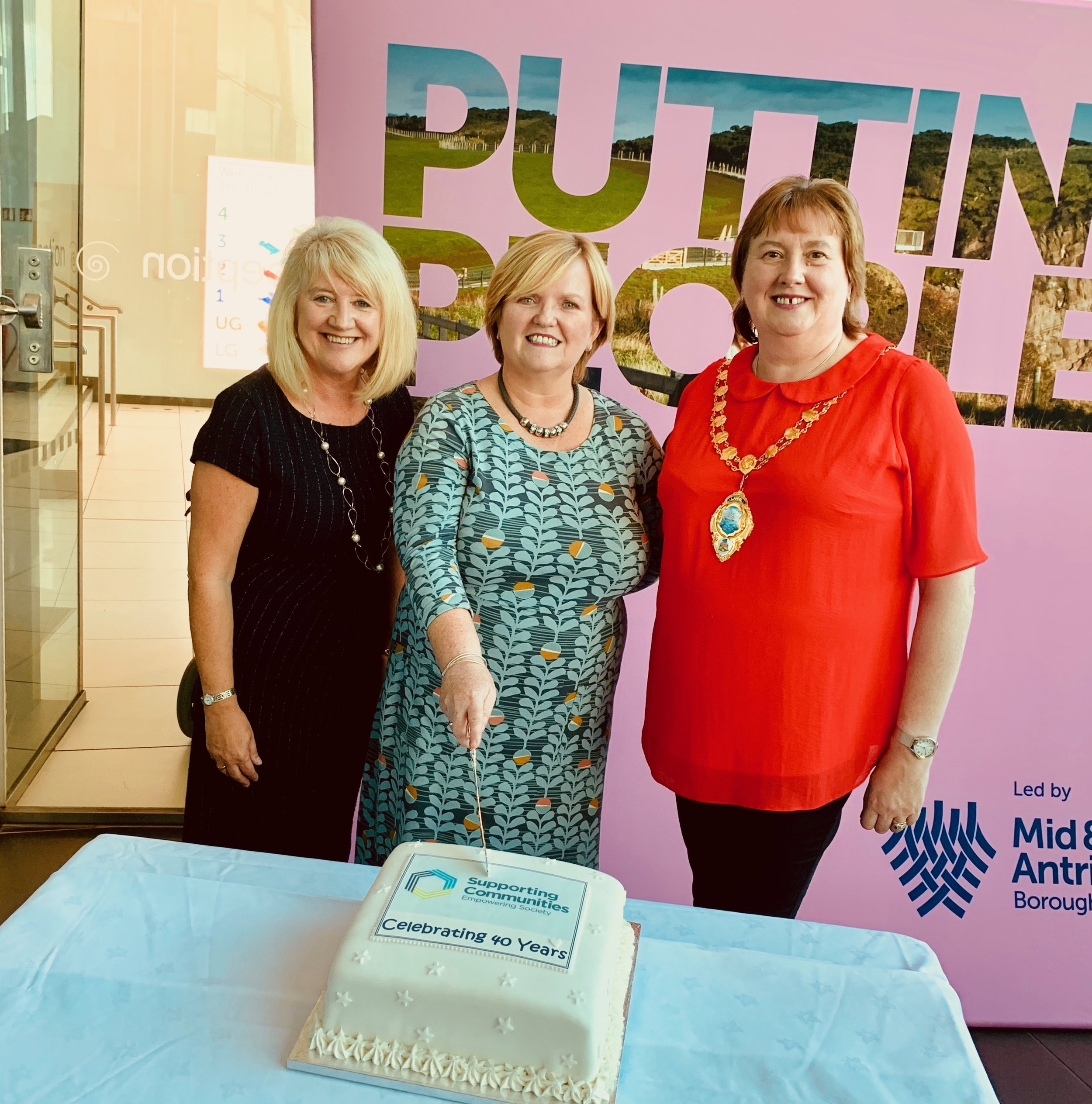 Lorraine Campbell, Theresa Patton, and Cllr. Maureen Morrow make it official with an anniversary cake!