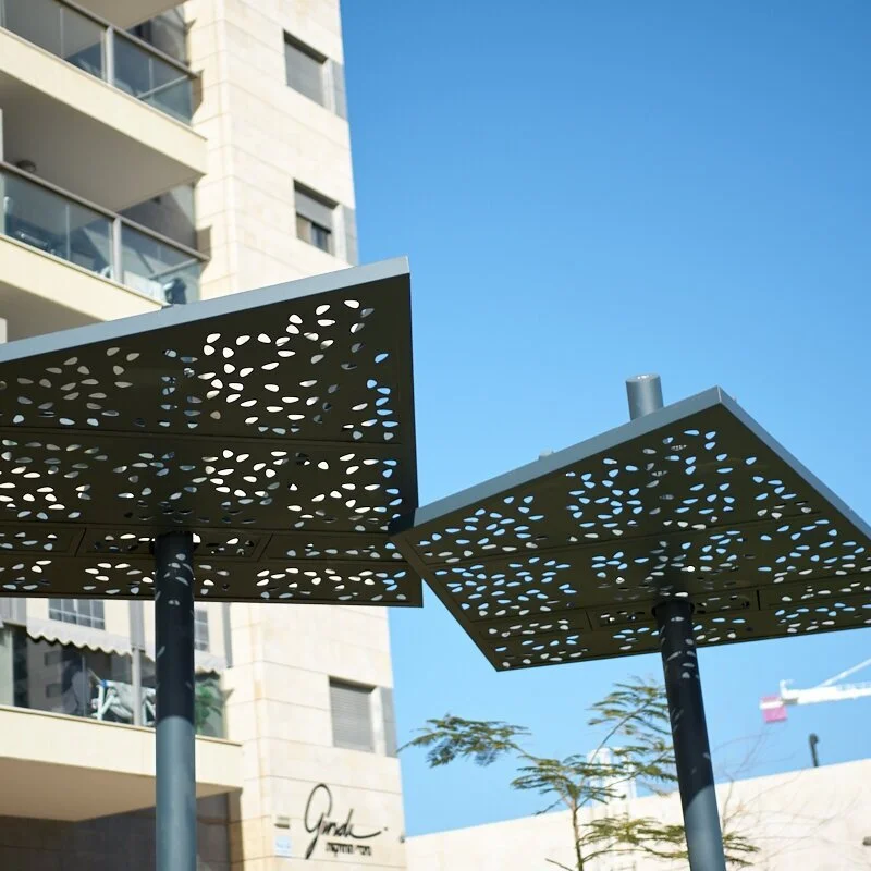 שתי פרגולות סנטיאגו עם גגות מתכת מחוררים בדוגמת טיפות, רקע בניין מגורים בכרמי גת