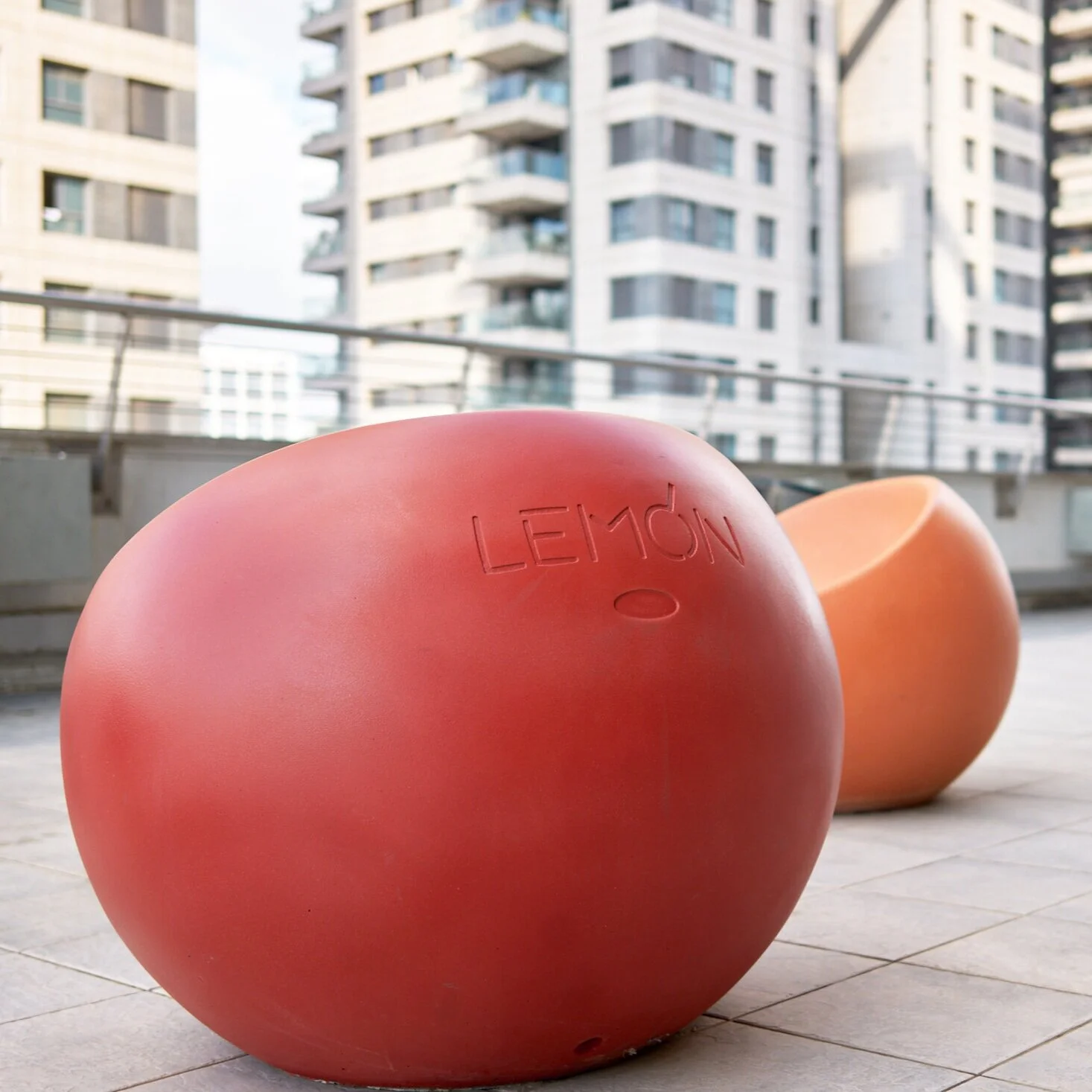 כיסא LEMON אדום בגודל מלא ברחבת גג, בניין מגורים ברקע