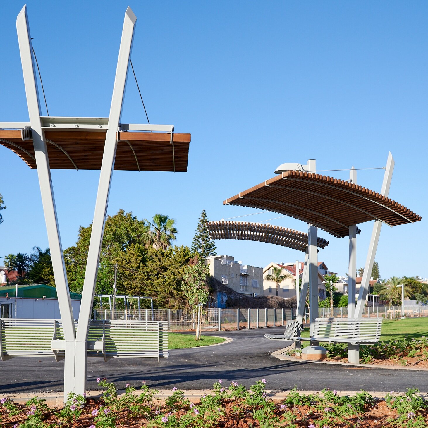 שלושה פביליוני הצללה מעץ ומתכת לאורך שביל במרחב ציבורי בגליל ים