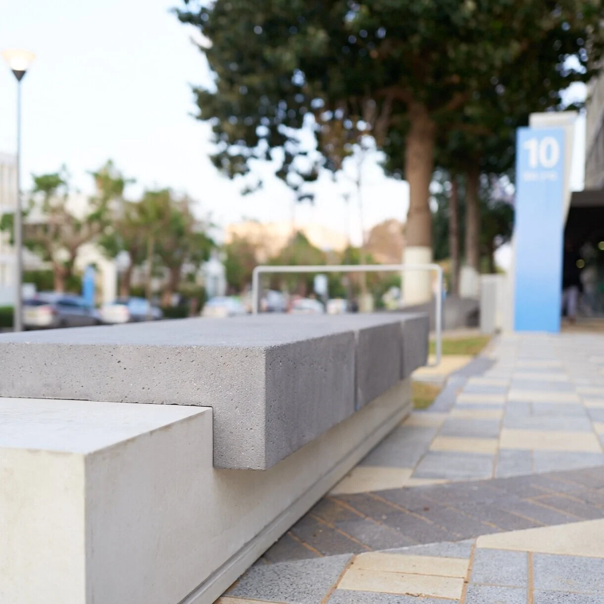ספסל בטון אדריכלי ארוך ברחבת בניין משרדים, מבט מקרוב על משטח הישיבה