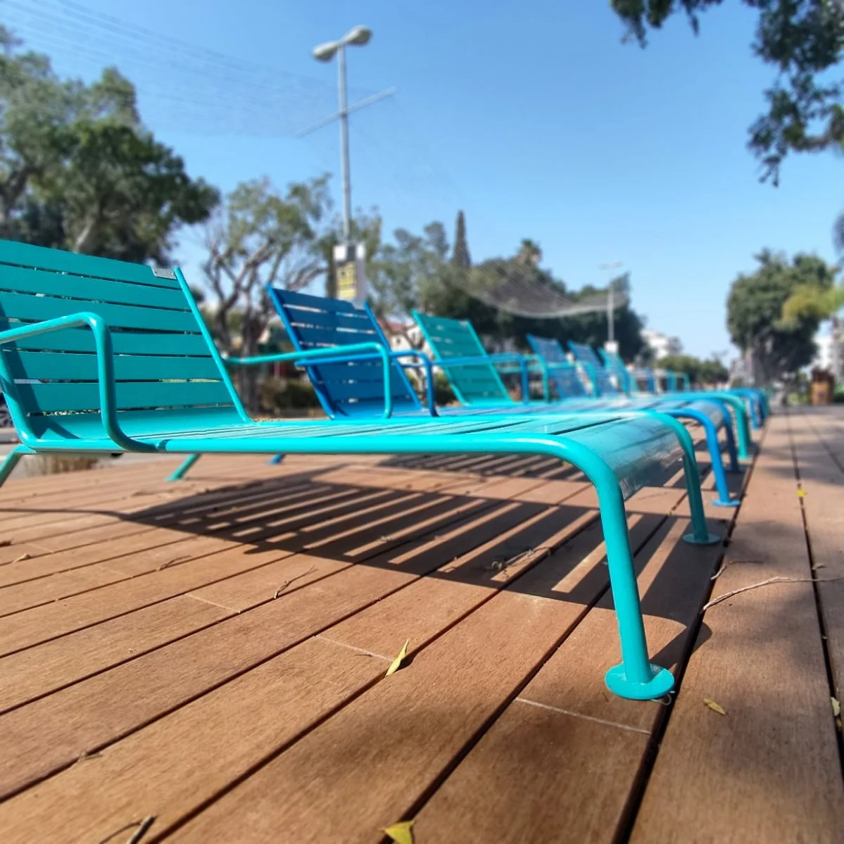 שכיבוני מתכת טורקיז על דק עץ חום לאורך רחוב אחוזה ברעננה