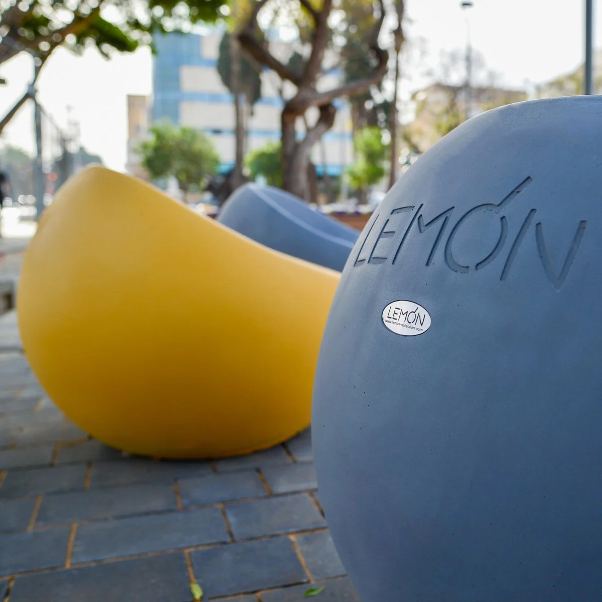 שורת פביליוני הצללה צהובים על עמודי מתכת לבנים על רקע שמיים כחולים ועצים