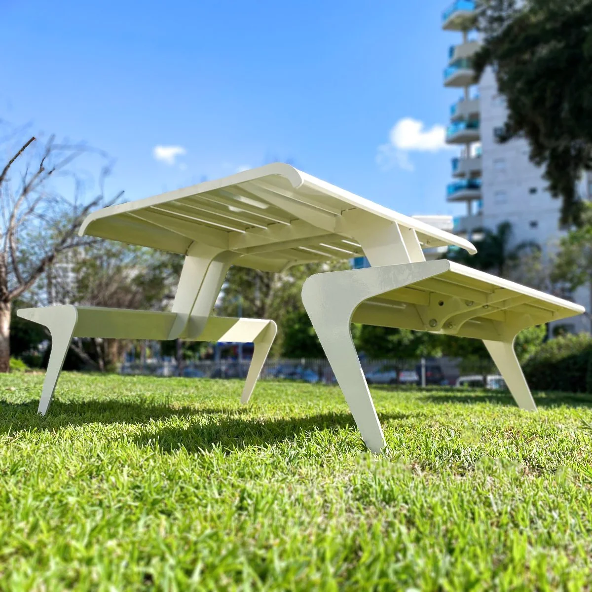 שולחן פיקניק לבן עם ספסל מתכת בפארק, מבט קרוב על פרופיל הרגל