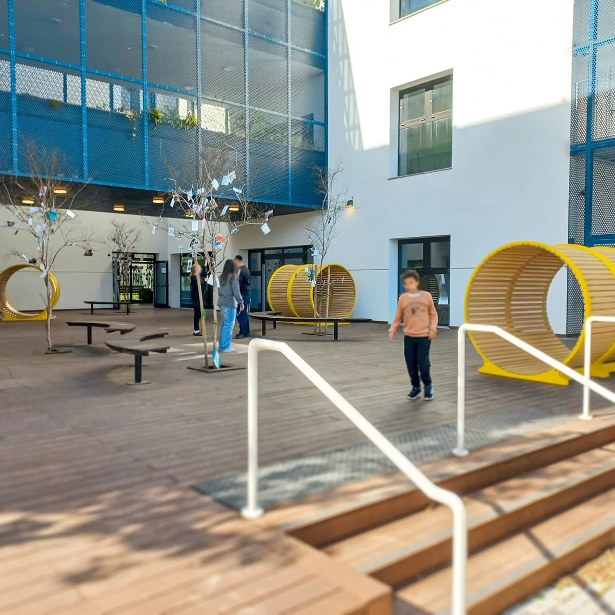 אלמנט ישיבה טונל עגול מעץ ומתכת צהובה עומד זקוף בחצר מרוצפת