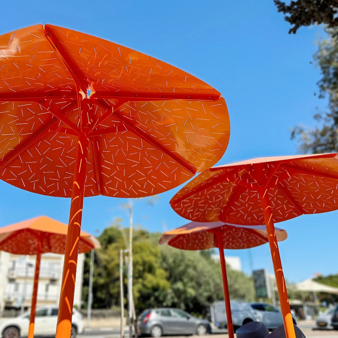 שני גופי הצללה מתכת כתומים בגדלים שונים עם צללים על הדשא