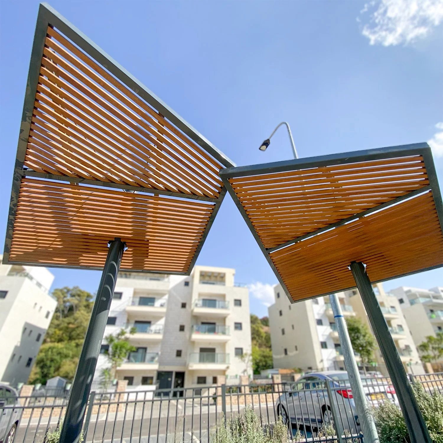 מבט מלמטה על גג הצללה סנטיאגו עם קורות עץ אופקיות ועמוד מתכת מרכזי
