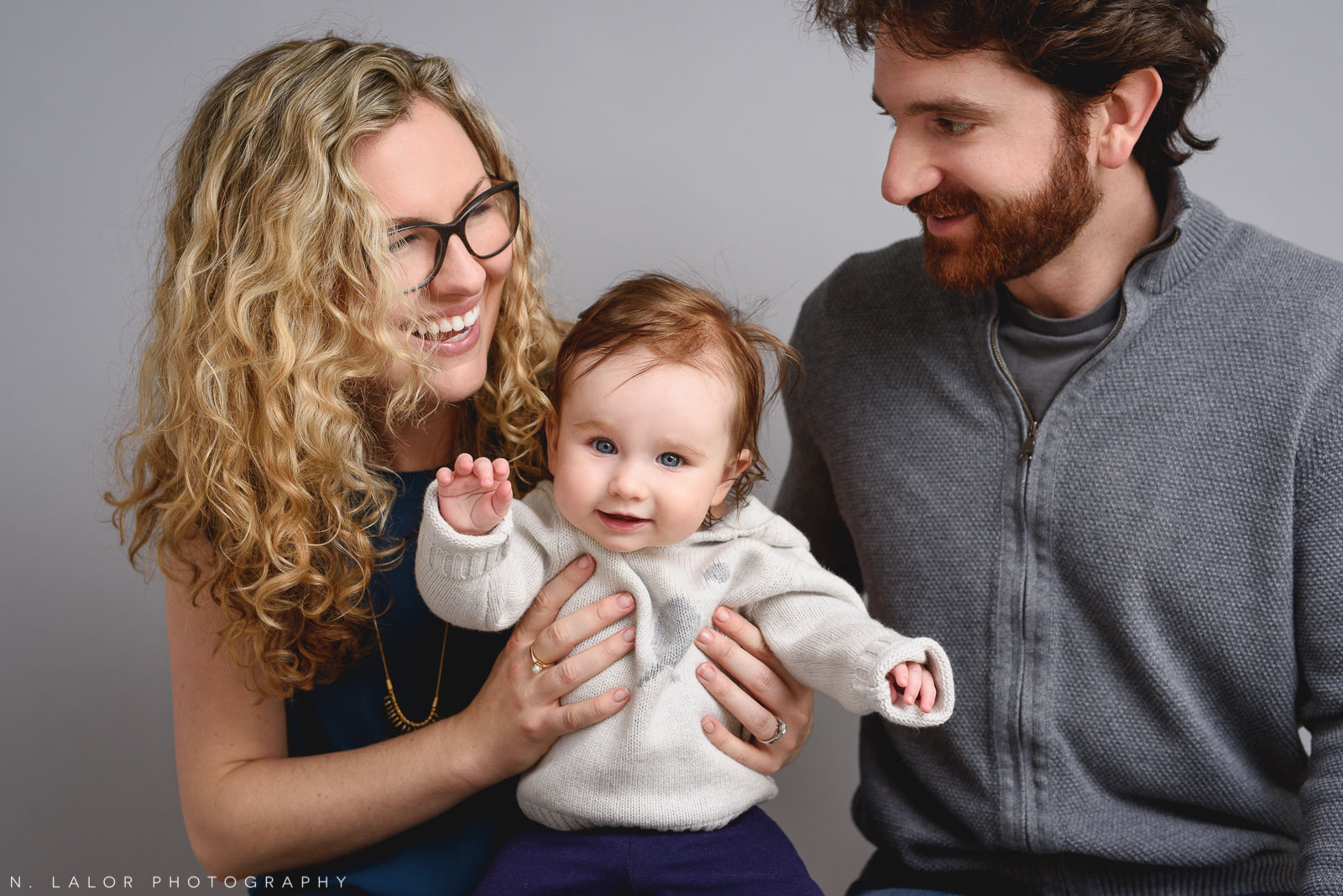 Happy family together with their baby girl. Family photo session by N. Lalor Photography. Studio located in Greenwich Connecticut.
