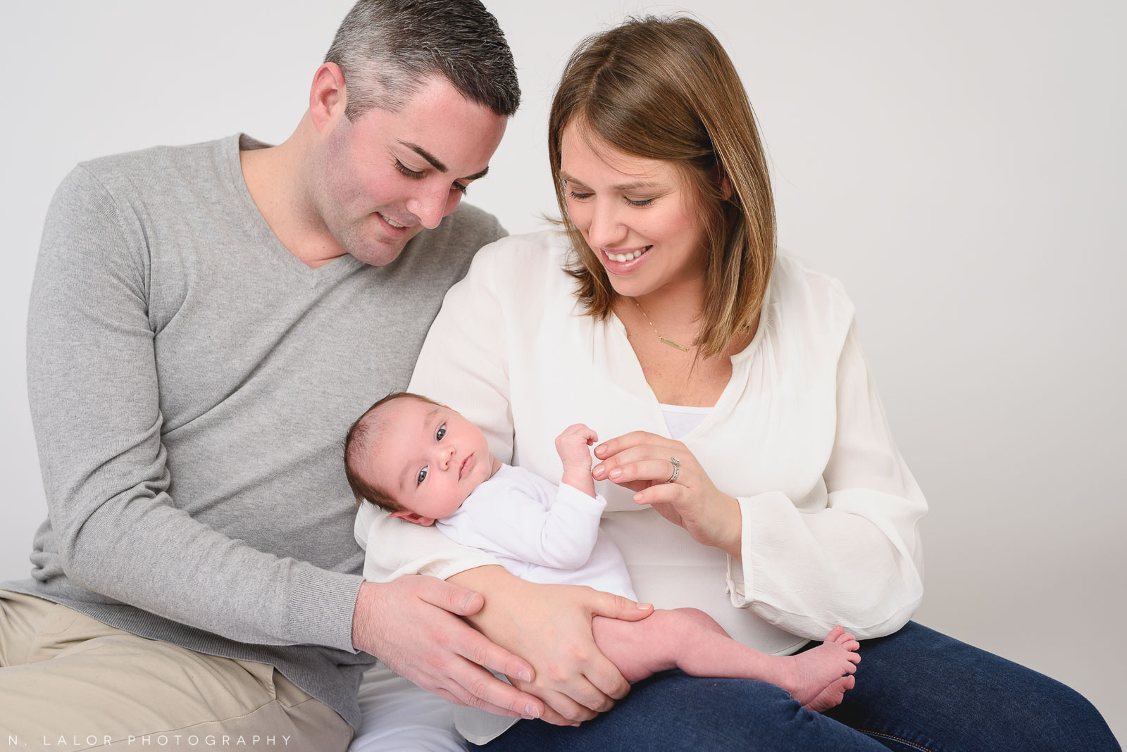 Family cradling their newborn. Newborn photo session by N. Lalor Photography. Greenwich, Connecticut.
