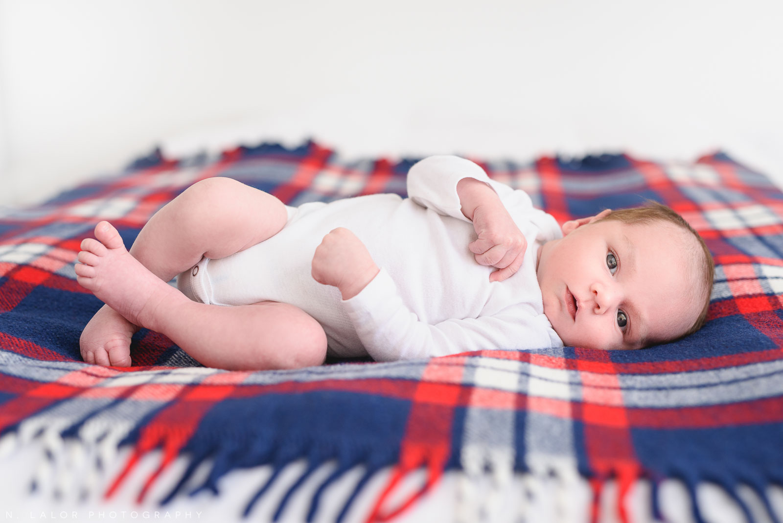 Newborn baby boy on his father's baby blanket. Newborn photo session by N. Lalor Photography. Greenwich, Connecticut.