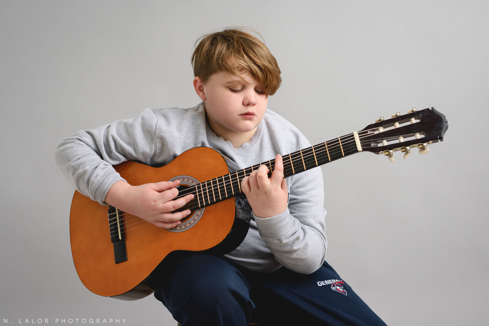 Benjy playing guitar. Teen family photo session with N. Lalor Photography. Greenwich, Connecticut studio photographer.