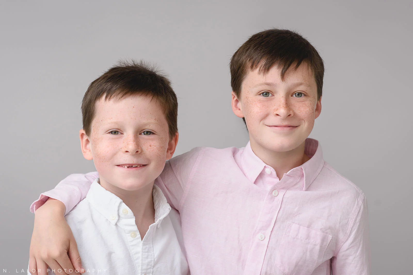 Image of two brothers being happy together. Studio portrait by N. Lalor Photography in Greenwich, Connecticut.