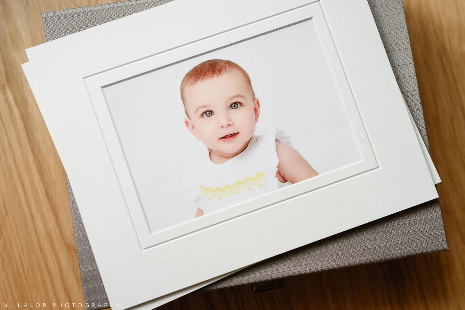 Image of a fine art print in a white mat. Portrait of a baby by N. Lalor Photography in Greenwich Connecticut.