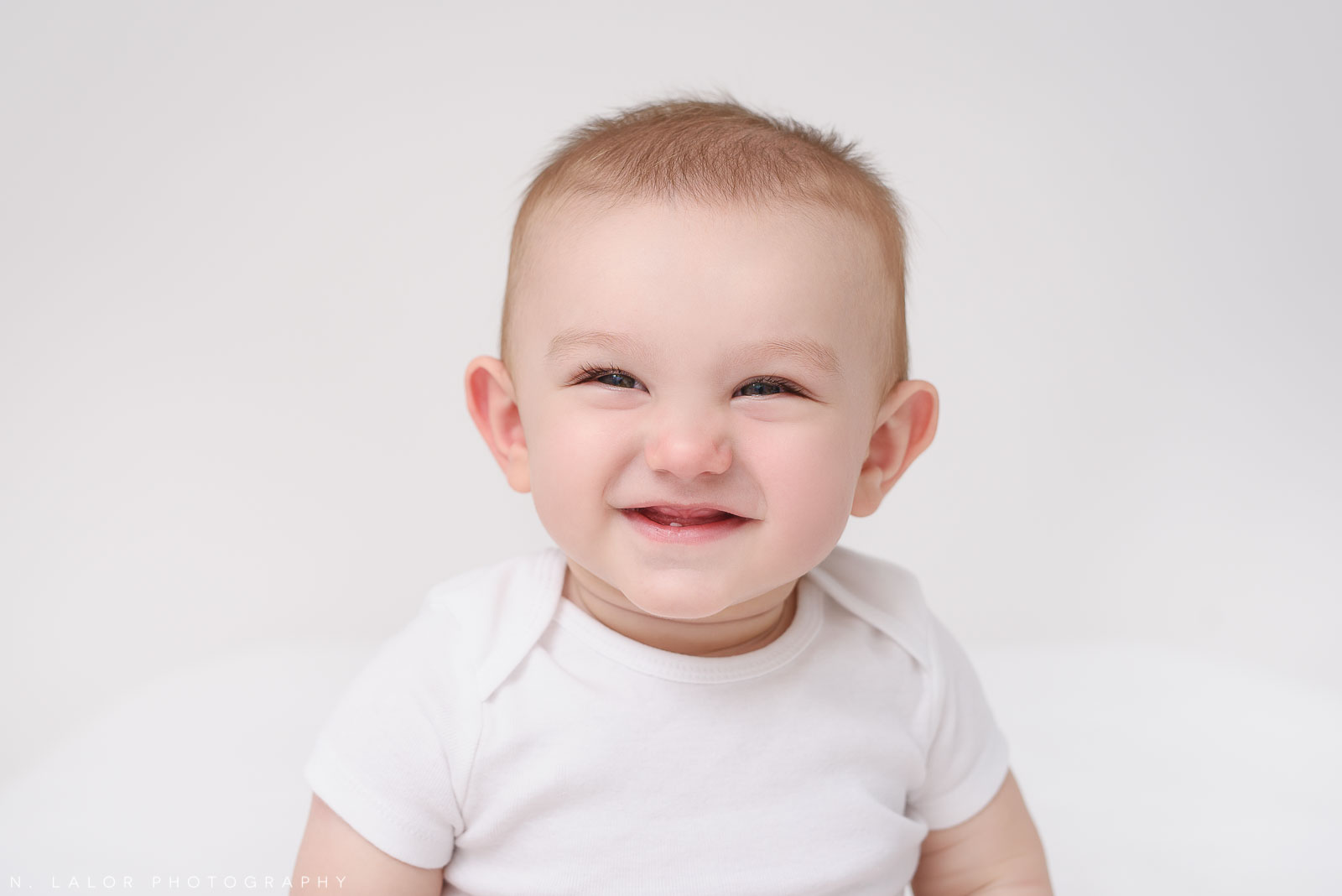 Image of an adorable baby smiling with one little tooth popping through. Studio portrait by N. Lalor Photography in Greenwich, Connecticut.