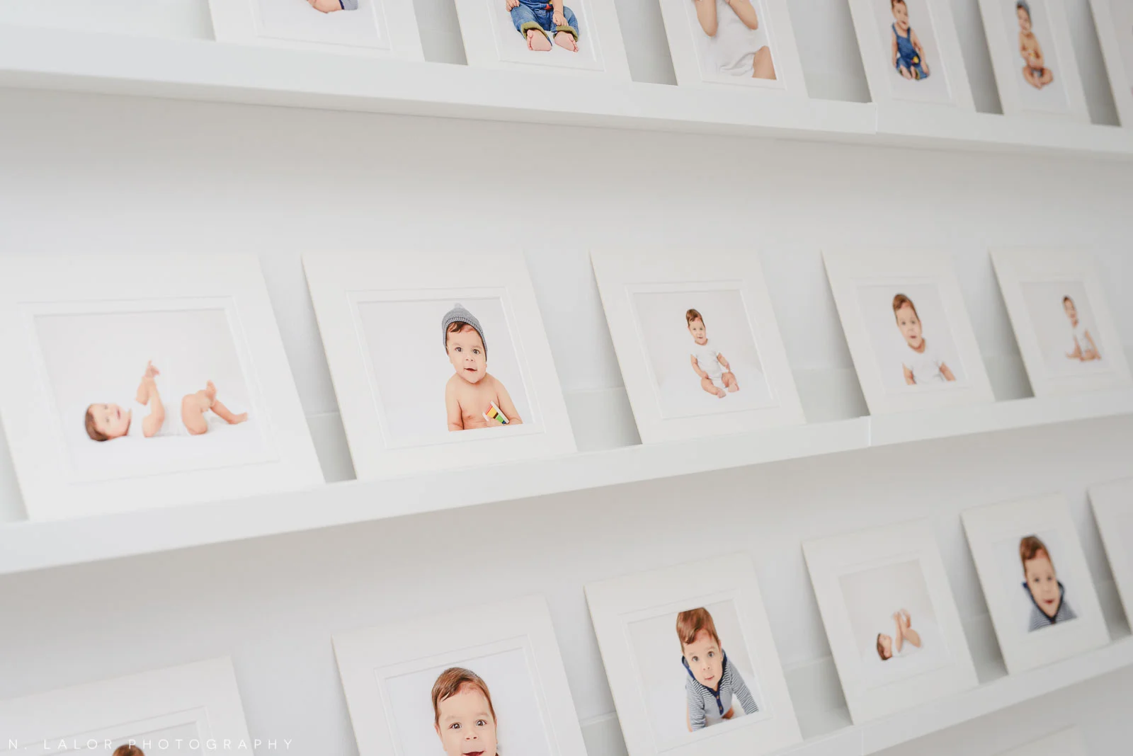Image of a wall of prints showing baby photographs. Studio baby portraits by N. Lalor Photography in Greenwich, Connecticut.