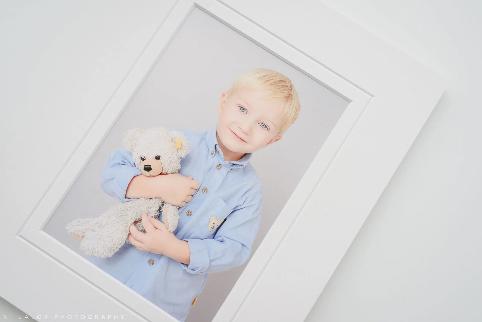 Image of a printed portrait of a happy boy with his stuffed teddy bear. Studio child portrait by N. Lalor Photography in Greenwich, Connecticut.