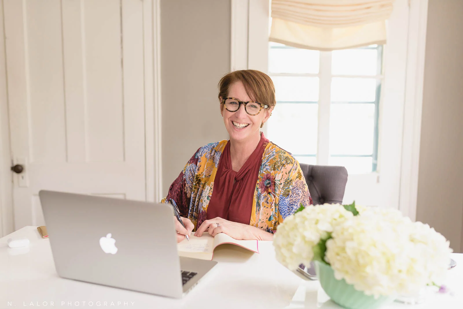 Image of a woman writing in her notebook while working in a home office. Portrait by N. Lalor Photography, Westport, Connecticut.