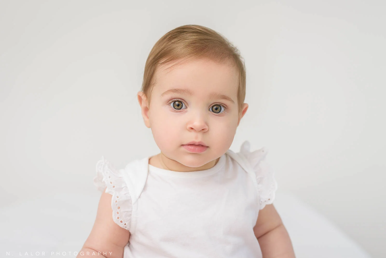 Image of a baby girl looking at the camera. Studio baby portrait by N. Lalor Photography in Greenwich Connecticut.