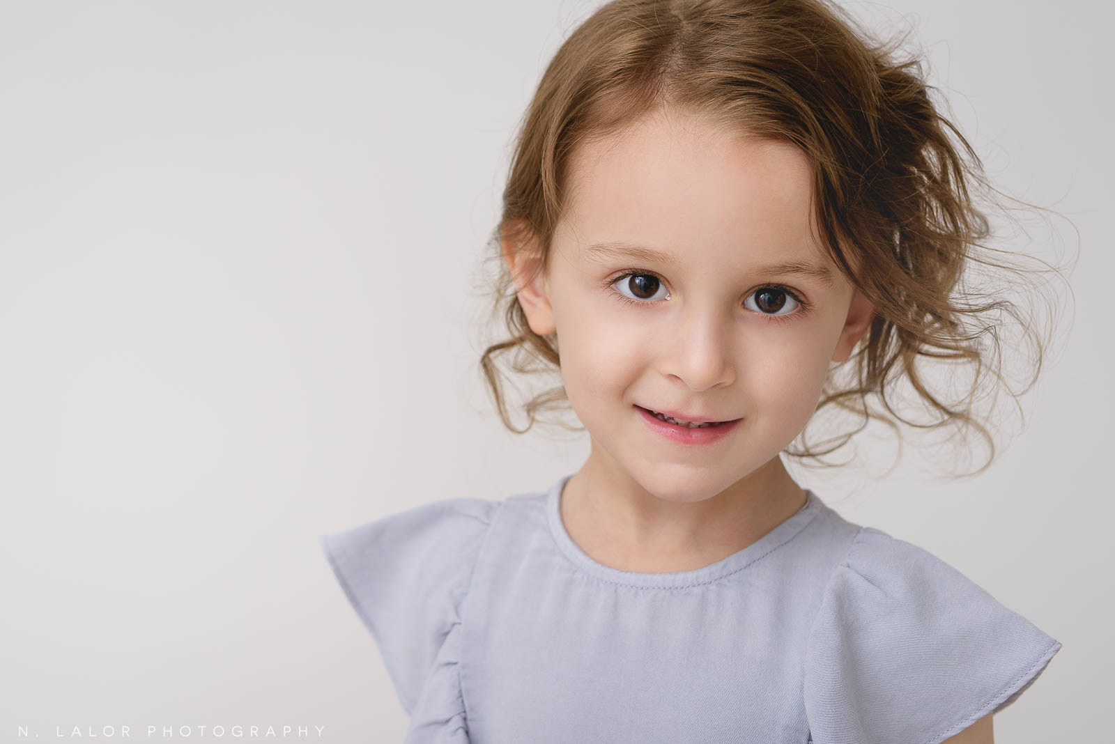 Image of a girl looking at the camera. Studio child portrait by N. Lalor Photography in Greenwich Connecticut.