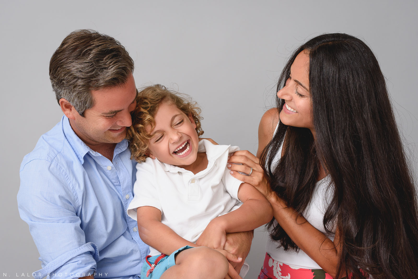 Image of Mom and Dad with their young boy, laughing. Studio family portrait by N. Lalor Photography in Greenwich, CT.