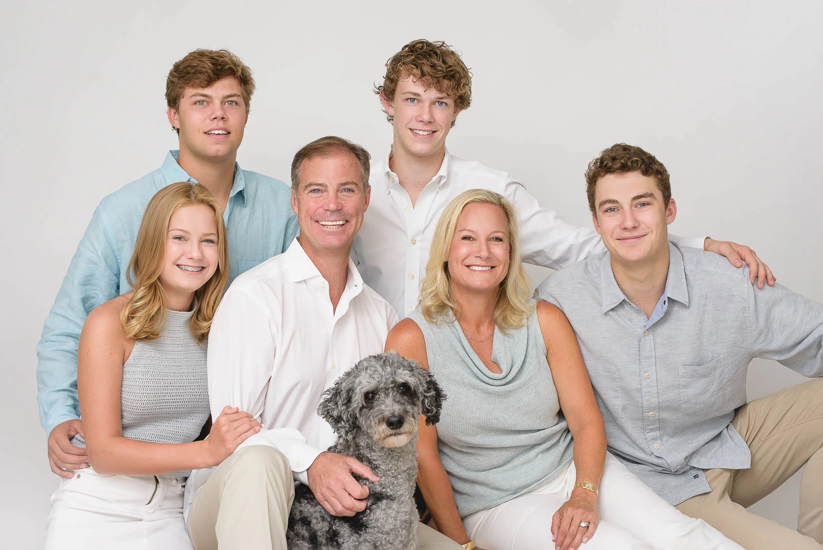 Studio image of a large, six-person family with teenage children and their pet dog. Photo by N. Lalor Photography. Studio in Greenwich, Connecticut.