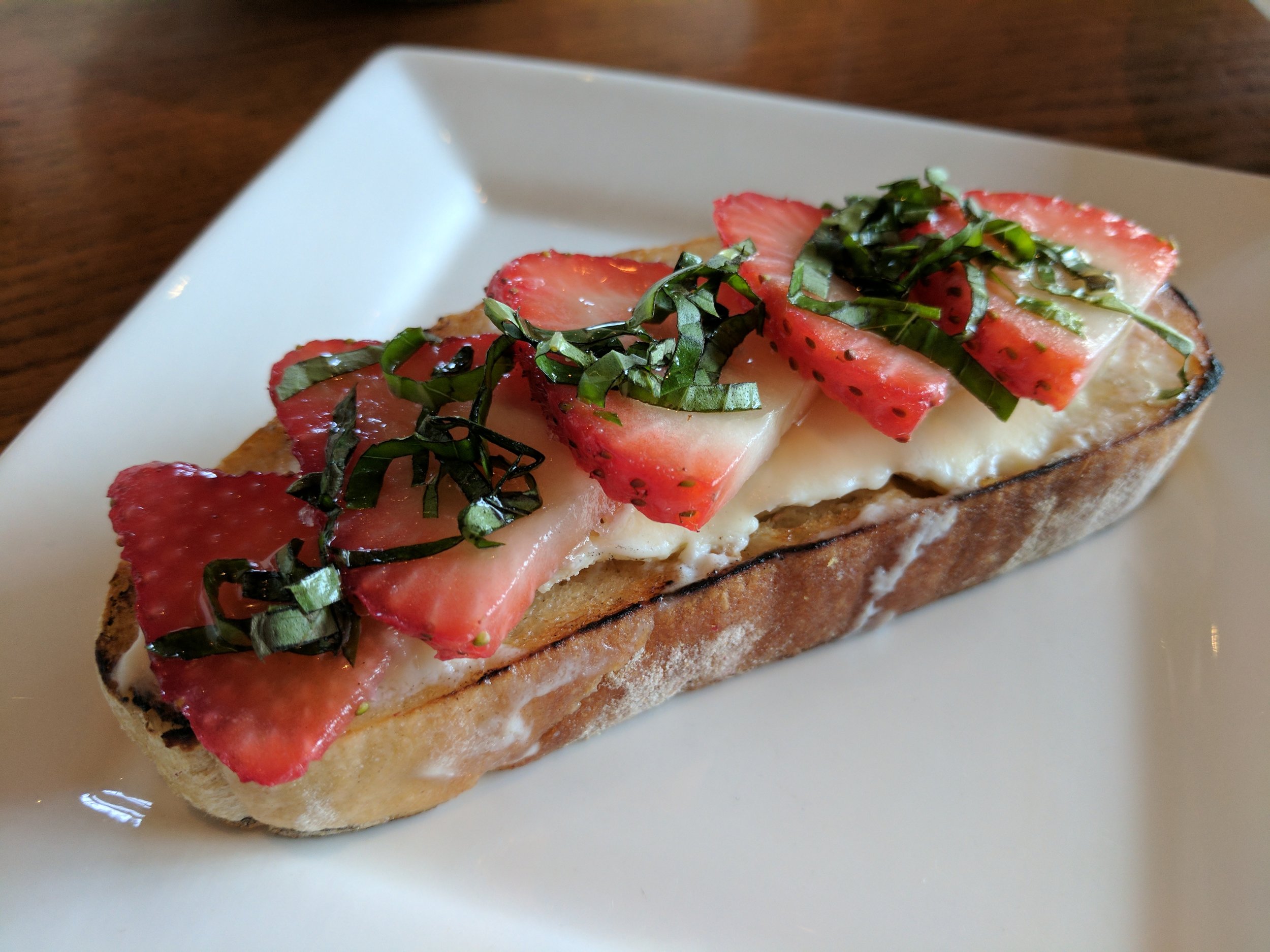 Fresh strawberries sliced over mascarpone cheese, topped with fresh basil and a drizzle of honey.