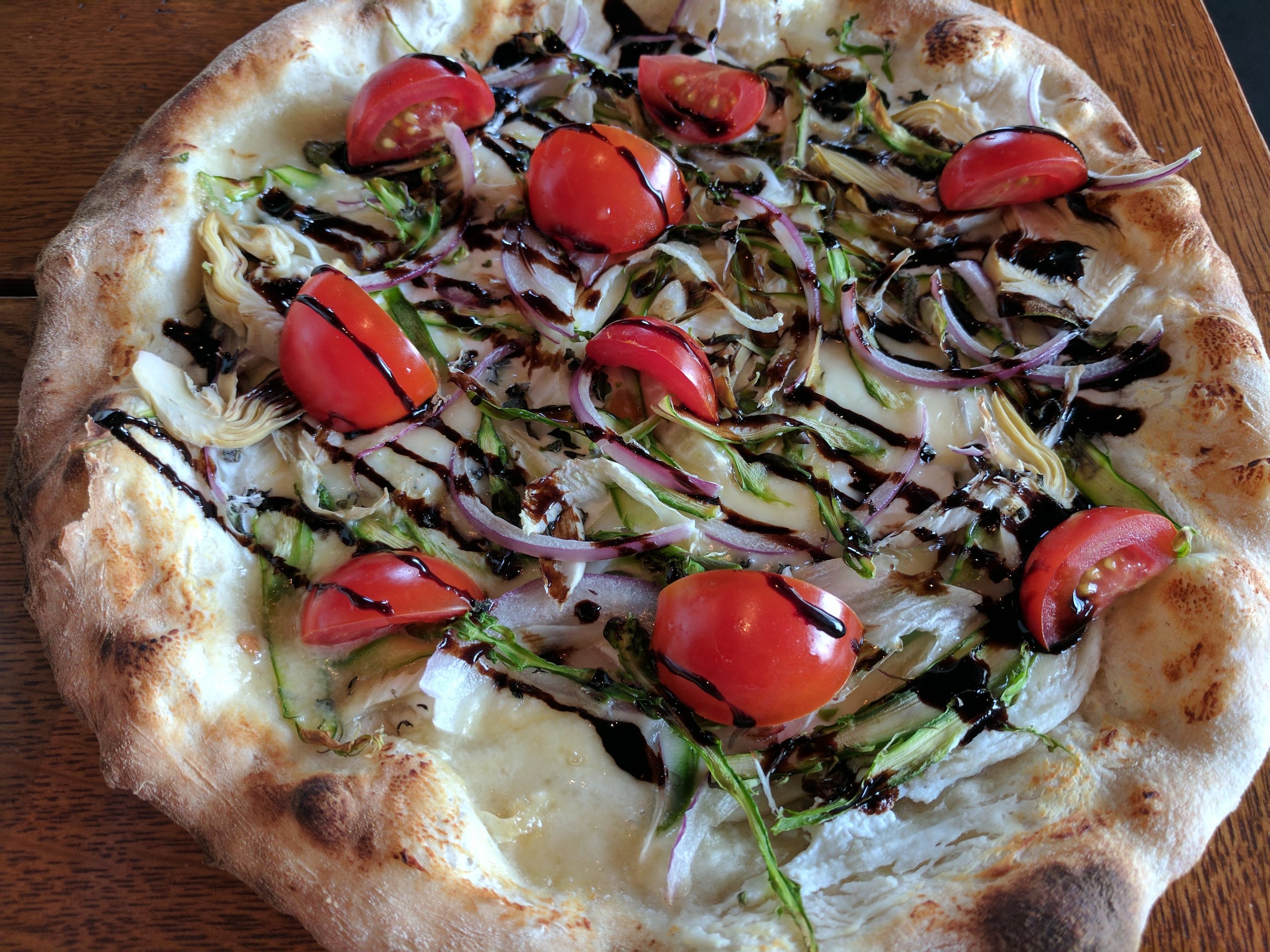 Artichoke hearts, shaved asparagus, red onion & cherry tomatoes, on top of talleggio cheese pizza.