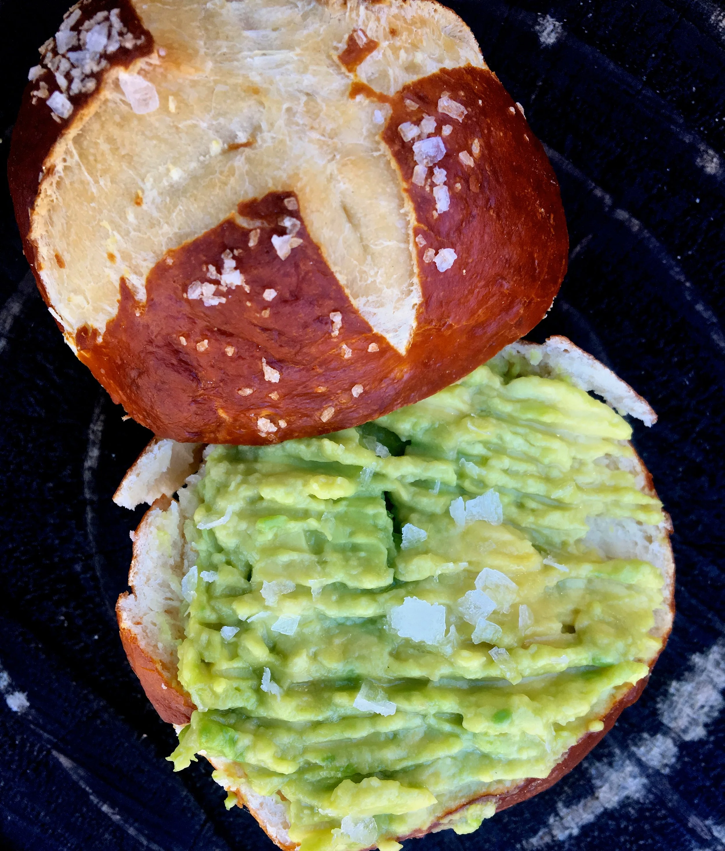 Pretzel roll with avocado, maldon salt and olive oil.