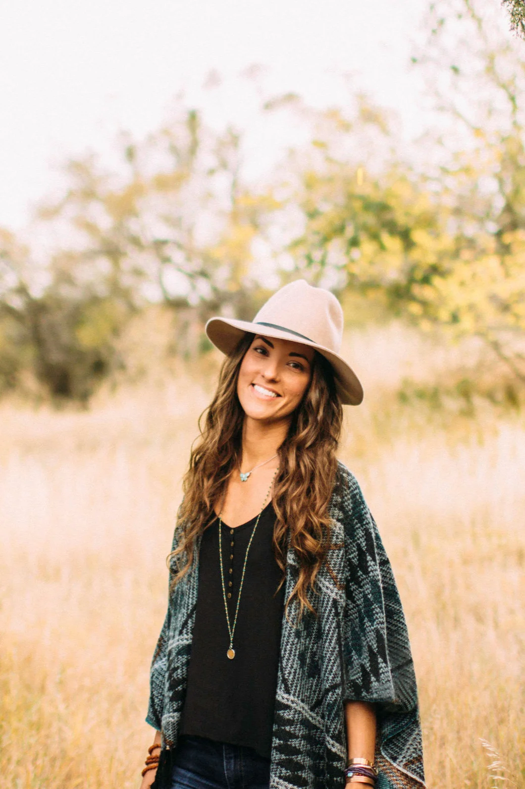 Beth standing in a field in autumn, wearing a felt hat.