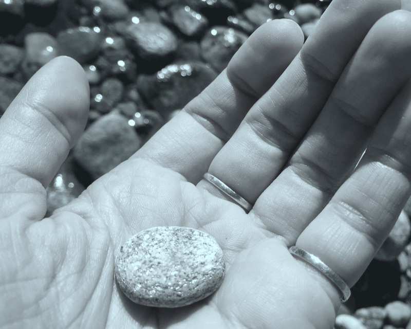Close up of Beth's hand holding a river rock.