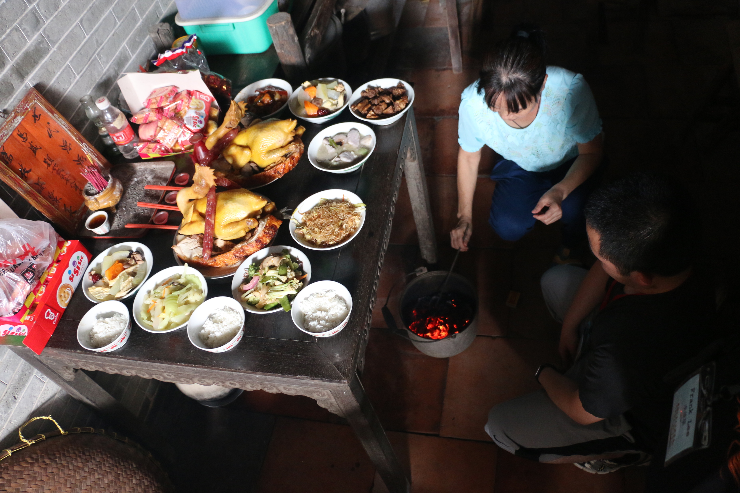 burning paper money in front of a table of food offerings. 