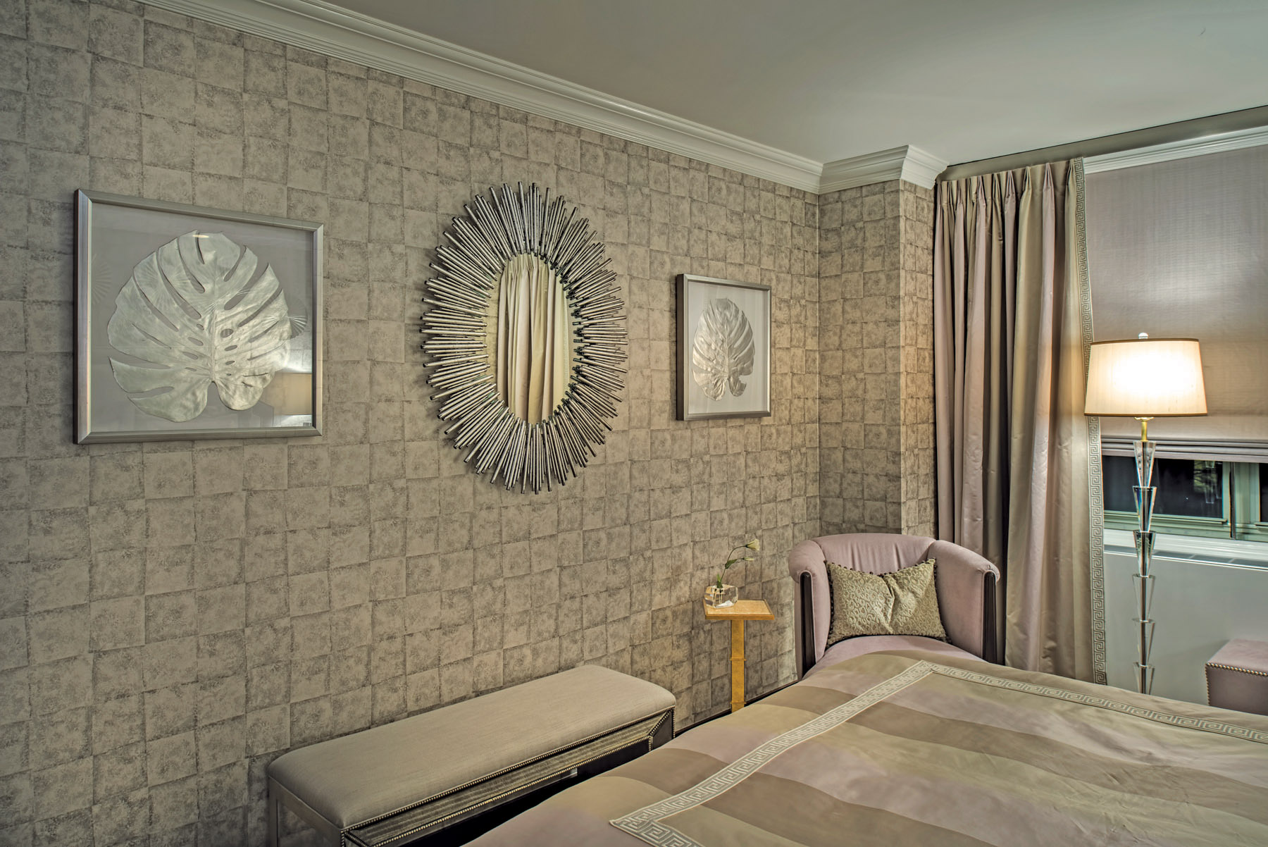 The mirror is a sunburst in silver metal flanked by silver leaf motif wall décor.