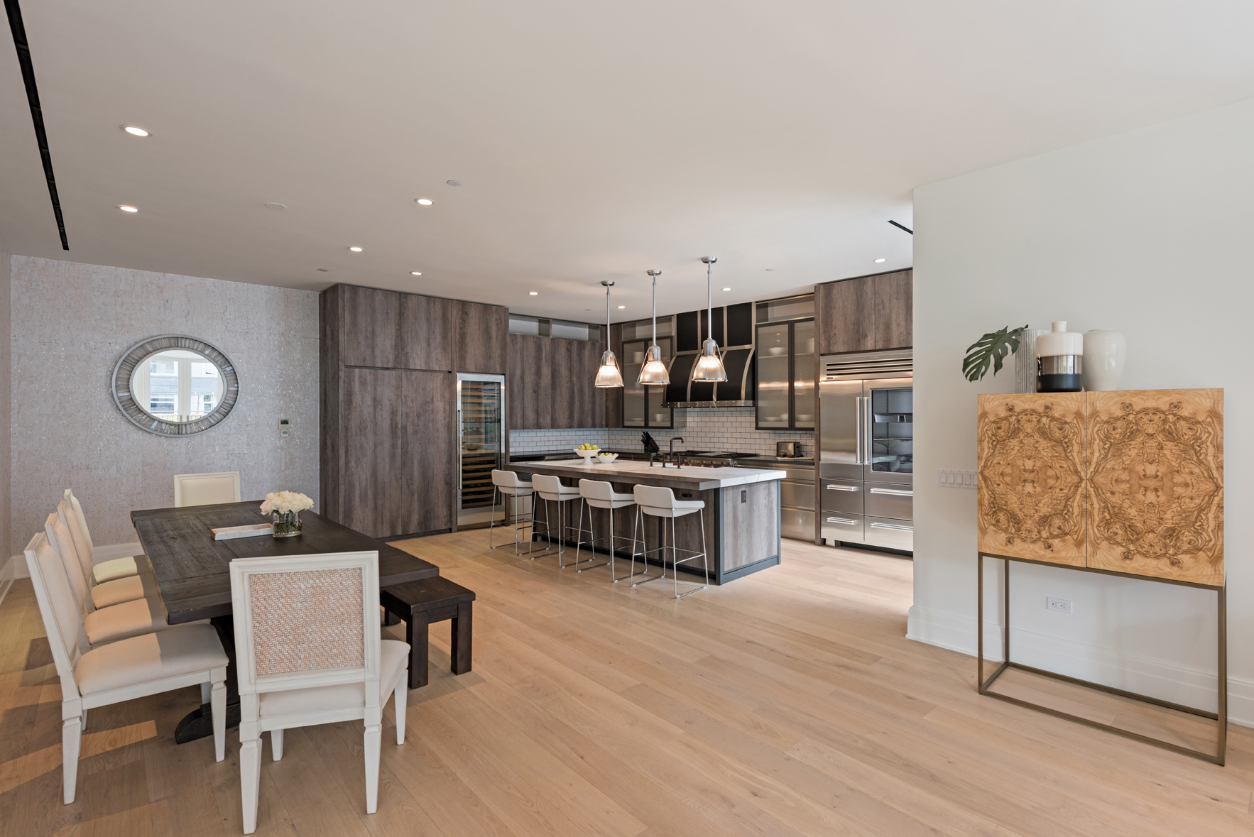 You always want a kitchen with the capacity to entertain. Here there are a variety of different seating options for all who enter, with an open path of conversation whether one is cooking or enjoying the food. Different elements of wood from cabinetry, to table and the accessory storage accentuate the bright hardwood flooring – producing a comfortable, appetizing tone in a modern space