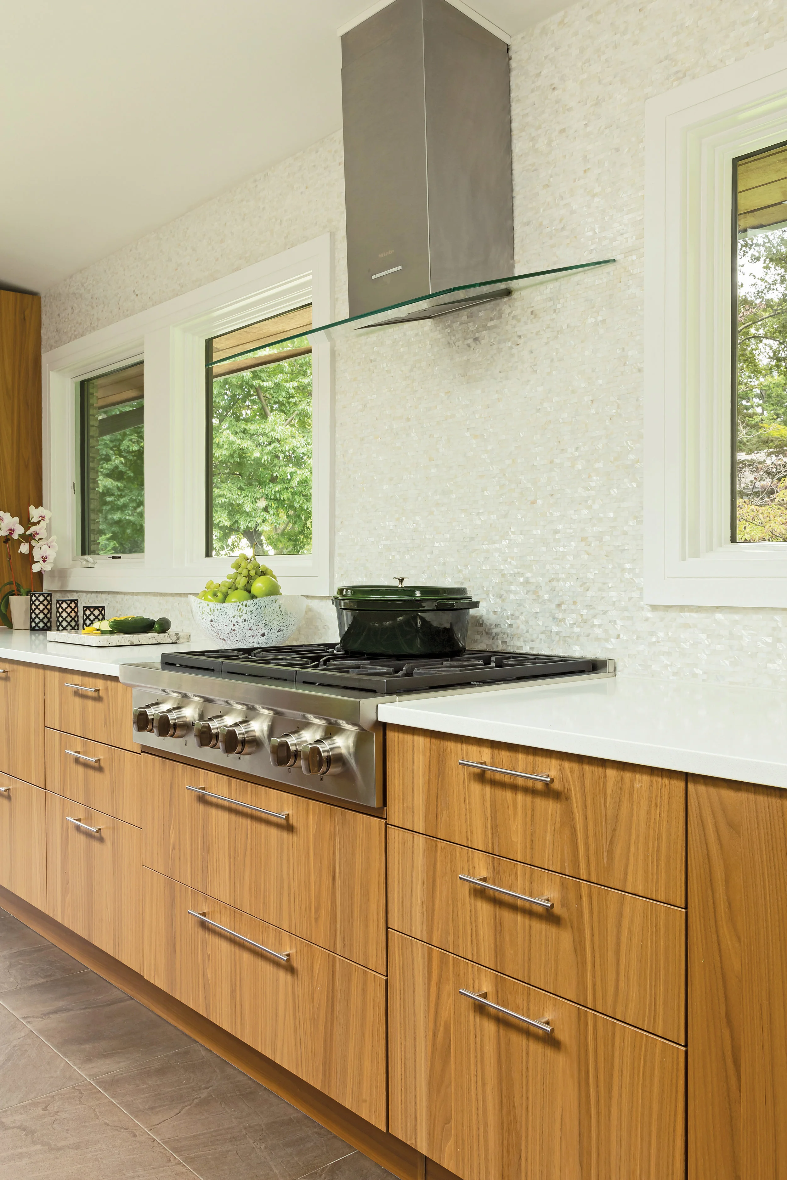 Wolf range and hood became the axis of the room in this one-of-a-kind kitchen with custom, book-matched vertical grain walnut cabinets imported from Italy. Mother of pearl backsplash creates spa like feel.