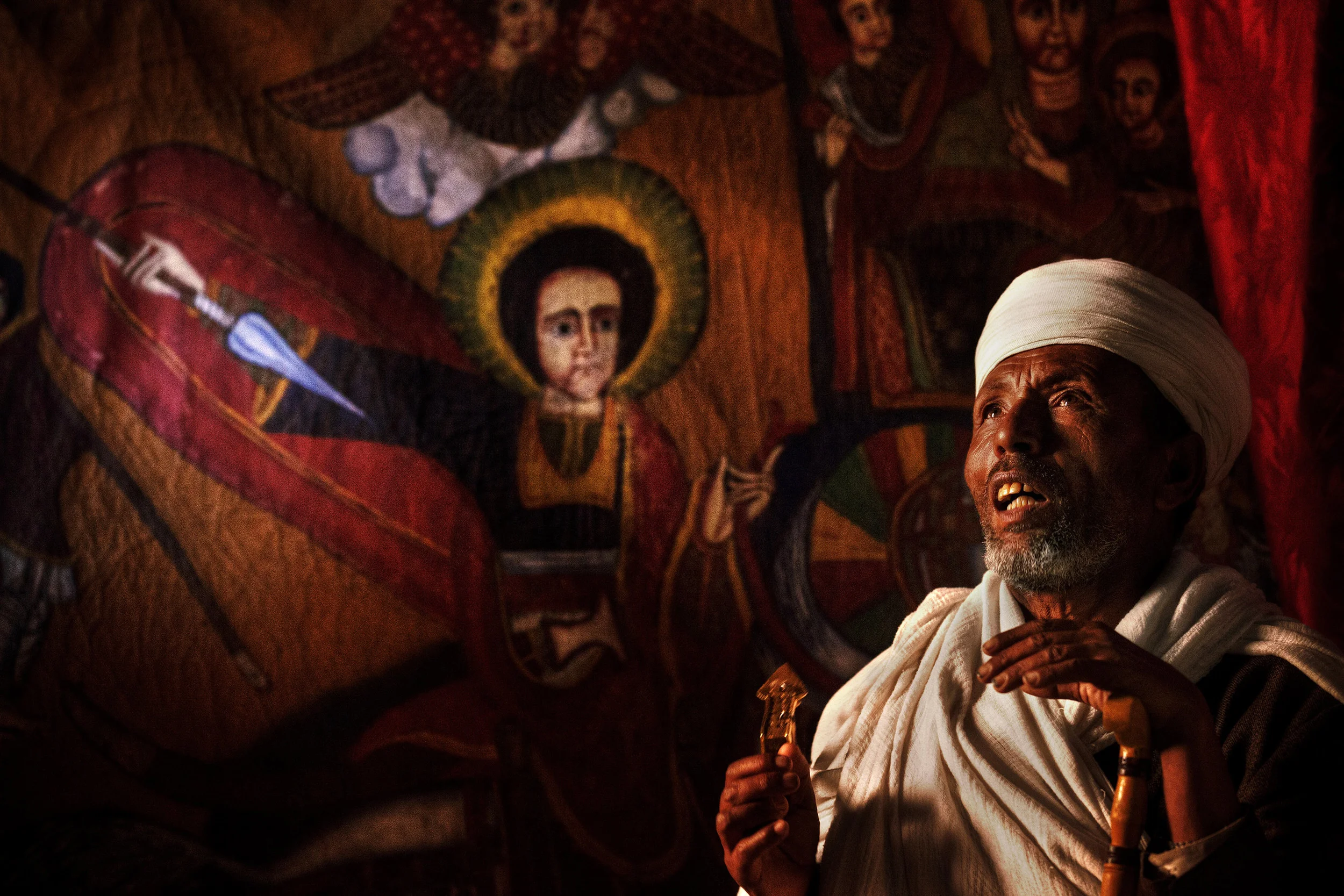 Priest-and-a-painting-of-Saint-George-in-a-rock-church,-Lalibela,-Ethiopia.jpg