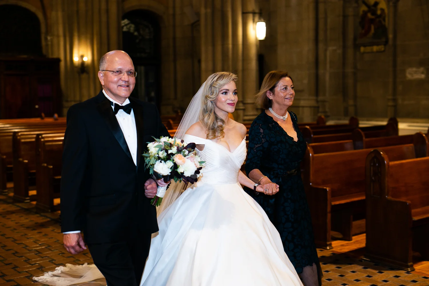 Bride and her parents walking down the aisle.